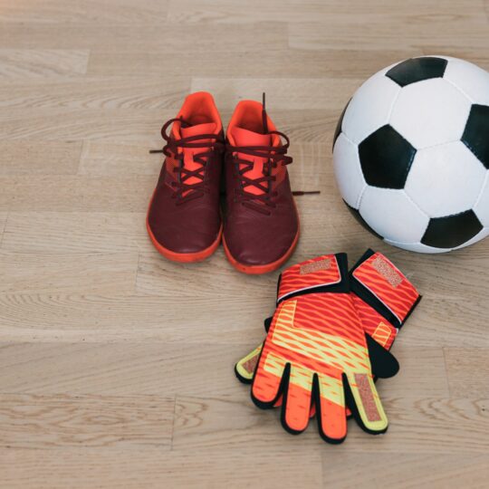 Goalkeeper gloves, soccer shoes and soccer ball ready for the game