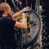 Mechanic repairing bicycle wheel tire in a workshop.