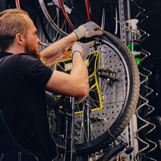 Mechanic repairing bicycle wheel tire in a workshop.